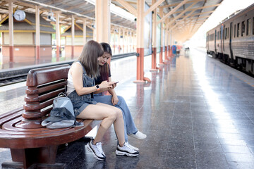 Two young woman traveler tourist  booking train queue by smartphone . Active and travel lifestyle concept