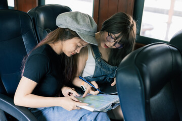 Two young women looking at a map while traveling by train