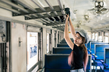 Female tourist putting luggage on the top shelf on train. travel and transportation concept.
