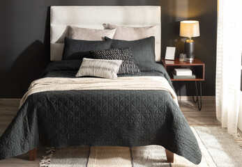 a large bed with two nightstands on each side and a dark gray coverlet