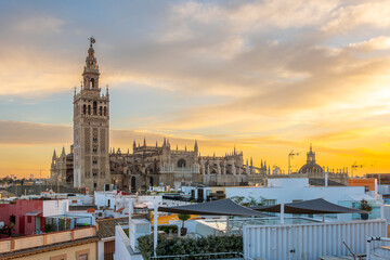 Sunset view from a rooftop overlooking the Andalusian city of Seville, Spain, with the Giralda Tower and the great Seville Cathedral in view over the skyline.