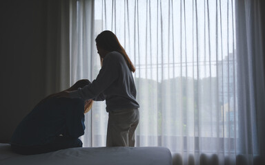 A woman touching her friend shoulder to comforting and giving encouragement in bedroom