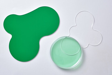 Against the white background, some acrylic sheets decorated with a petri dish containing green liquid. Scene for advertising with blank space for design and product display. Top view