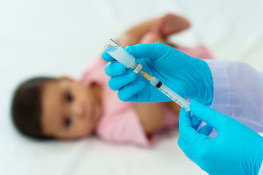 doctor drawing syringe and preparing vaccine giving injection to baby