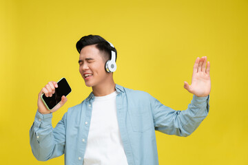 Young man headphones listen to music sing song record voices by cellphones isolated - 615647242