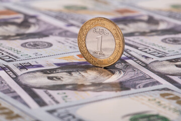 A coin of 1 riyal of the Kingdom of Saudi Arabia against the backdrop of a cupbra of 100 US dollars
