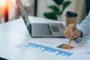 Close up of businesswoman hand holding pen and pointing at financial document Financial charts to...