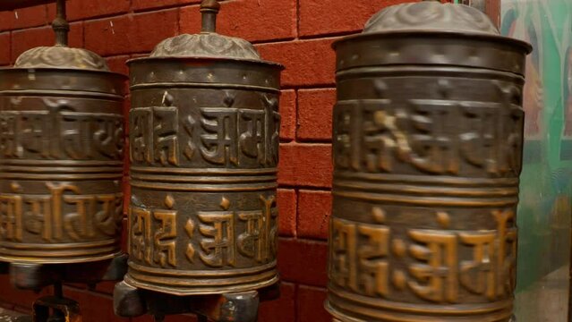 Close up of person with tattooed arm spinning Buddhist prayer wheels at temple 