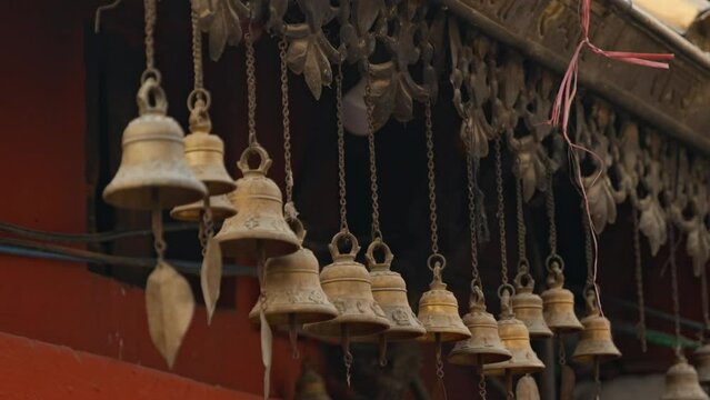 Row of hanging brass wind bells outside temple in Kathmandu, Nepal