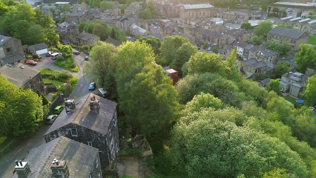 Flying over the center of todmorden revealing the todmorden town hall , during golden hour on a sunny mid week evening 
