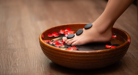 Woman soaks her feet in a bowl with flower petals