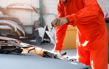 Mechanic checking engine oil dipstick parked at service center