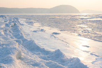 Winter beautiful landscape of frozen Japan Sea covered with ice and snow on a sunny day. Beauty of nature concept. Postcard from Russia with selective focus