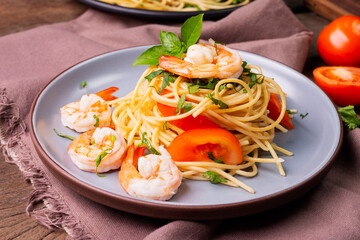 Stir-fried spaghetti or stir-fried noodles Tomato sauce and prawns on a plate and tomato basil on wooden table background, top view