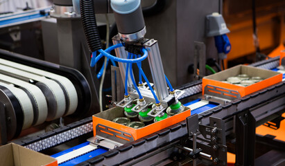 Automated robot arm lifting food can to conveyor belt in food industry.