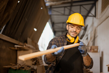 Happy carpenter worker working look at wood panel material for making masterpiece wood crafting...