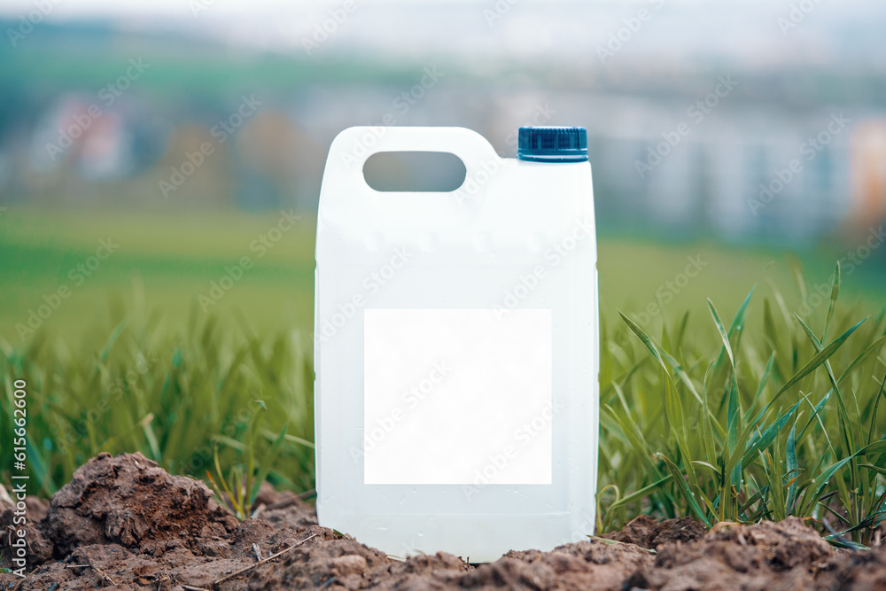 Poster white plastic container with agricultural chemicals or fertilizers on a green field