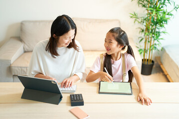 Obraz premium タブレットPCを使って仕事をする女性と遊ぶ女の子