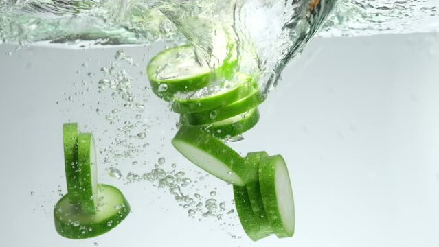 Many Winter melon (Benincasa hispida) slices falling into clear water with splashes on white background. Fresh fruit concept