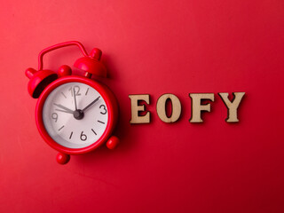 Red alarm clock and wooden word with the word EOFY