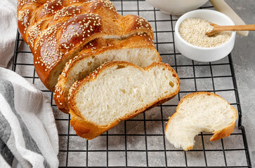 Homemade challah bread with sesame seeds, butter and jam on a grey concrete background. Sweet...