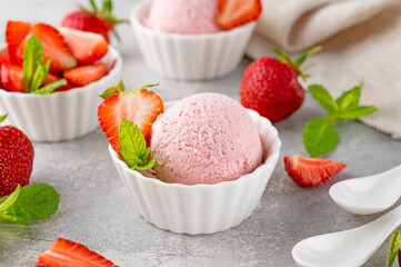 Strawberry ice cream with fresh berries in a bowl on a gray concrete background. Selective focus