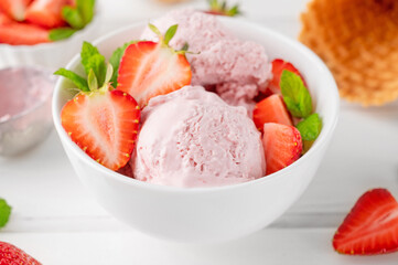 Strawberry ice cream with fresh berries in a bowl on a white wooden background. Selective focus