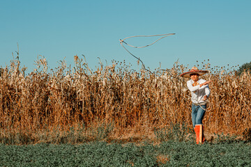 A cowboy in the expansive prairie, wielding his lariat amidst a bountiful harvest