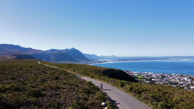 MTC cyclist on mountain road overlooking scenic coast and bay. Drone tracking