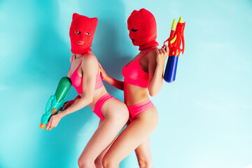 Two beautiful sexy women in red underwear. Models wearing bandit balaclava mask. Hot seductive...