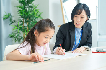 勉強する女の子とサポートするスーツ姿の女性