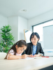 勉強する女の子とサポートするスーツ姿の女性