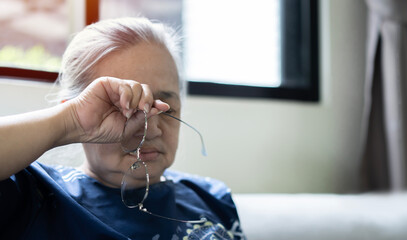 Close up of unhealthy elderly woman take off glasses massage eyes suffering from strong migraine or headache