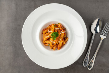 Penne pasta in tomato sauce, tomatoes decorated with parsley on a wooden background