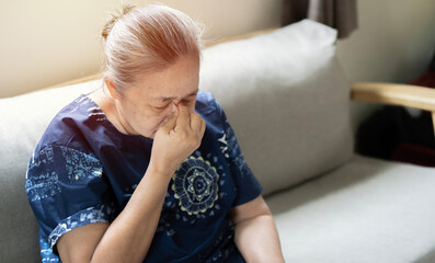 Elderly Asian woman crying wipes tears with hands feels unhappy