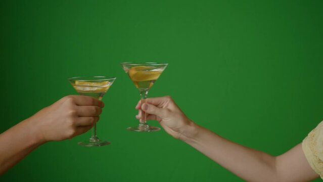 Hands with a cocktail on a green background make cheers