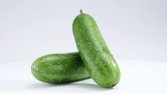 Two winter melon leaning against each other and rotating on a white background. Winter melon (Benincasa hispida) has the effect of clearing heat and cooling the body