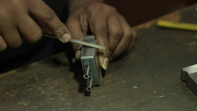 Close up of Worker hand sanding metal piece with rasp. Handheld