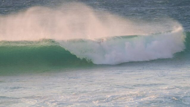 Surfer falling while catching a wave in ocean at sunset