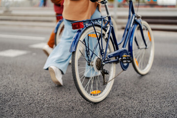 Fototapeta na wymiar Cropped picture of female traveler pushing her bike on the city street.