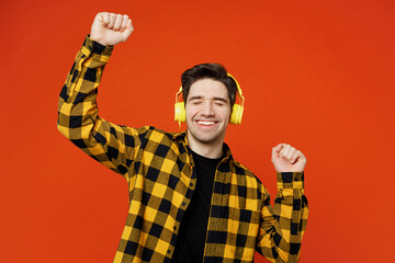 Young cheerful happy caucasian man wear yellow checkered shirt black t-shirt headphones listen to...