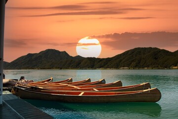 Sunset on the lake with traditional wooden canoe and mountain background, South Korea