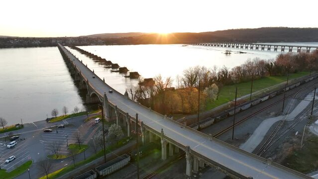 Downtown riverfront at sunset in the spring, with railways, freight trains and two bridges crossing the river.
