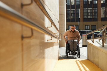 Young man with disability using ramp to move up the building - obrazy, fototapety, plakaty