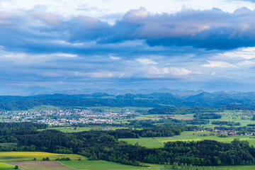 Fototapeta premium View of a forest, fields and village on the hills against a cloudy sky