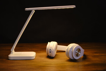 Headphones in the light of a modern table lamp. Place for text. Music concept.