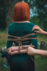 a man ties up a woman in green body and black tights with a natural rope japanese art of aeshetic shibari bandage kinbaku