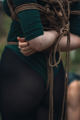 booty of a tied up woman in green body and black tights with a natural rope japanese art of aeshetic shibari bandage kinbaku
