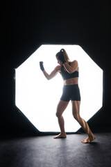 Fototapeta na wymiar Female boxer training in the dark ring. Slow motion. Silhouette. Boxing concept