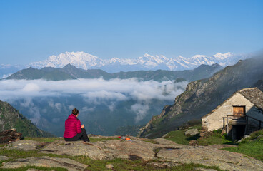 Hiker eating breakfast outside Bivacco Alpe Scardi during a sunny morning in Val Grande, Italy.